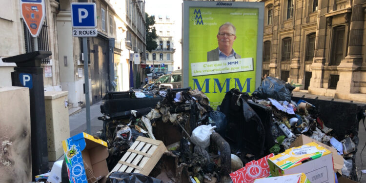 Des poubelles incendiées devant la préfecture sous le ragard de Patrick Eué (affiche) le patron du syndicat FO. Un condensé de Marseille (Crédit JFE/Gomet').